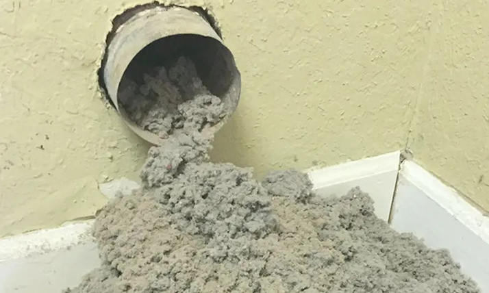 Show Me Air Duct Cleaning tech inspecting clogged dryer vent with flashlight