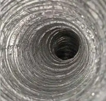 Technician cleaning ceiling air duct vent in O’Fallon commercial space