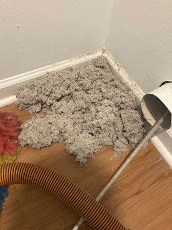 Technician using brush system to clean clogged dryer vent pipe in O’Fallon